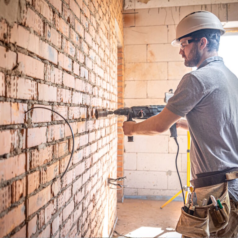 Ouvrier perçant un mur en briques
